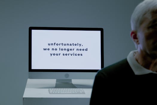 A computer screen displays a termination message, indicating job loss or unemployment.