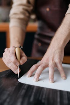 Skilled artisan using a tool to cut leather, showcasing craftsmanship and precision.